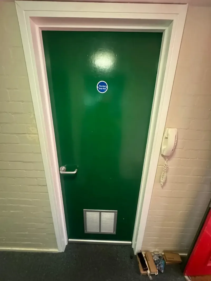 Remediated fire door with intumescent vent and keep-shut signage